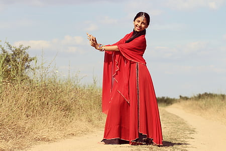woman wearing red tradition dress nearby brown grass