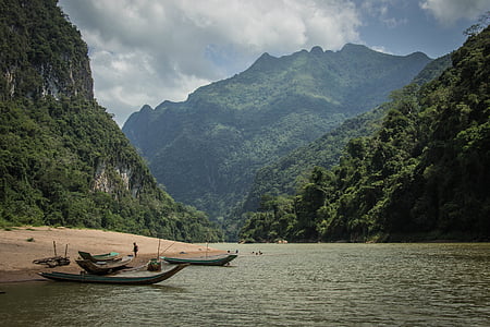brown wooden boats near shoreline and mountains