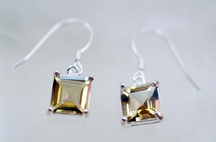 closeup photography of silver-colored hook earrings with yellow gemstone