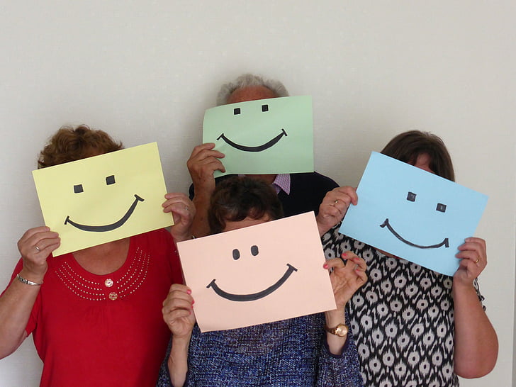 group of people holding smiley illustrations