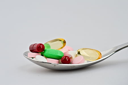 assorted medicine capsules on stainless steel spoon