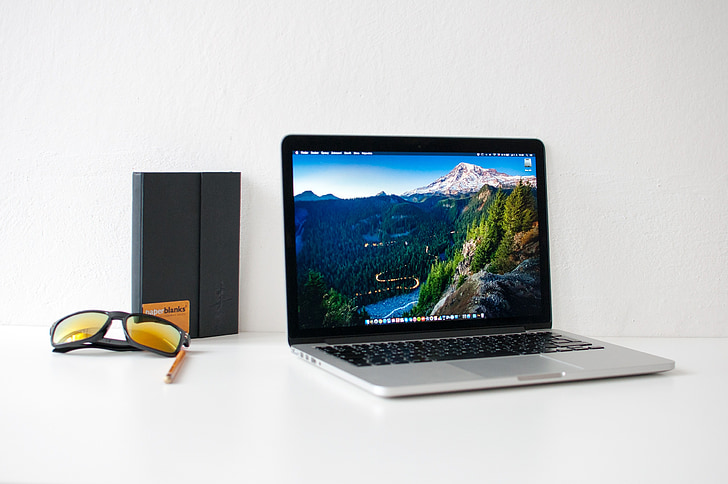 MacBook Pro beside black framed sunglasses