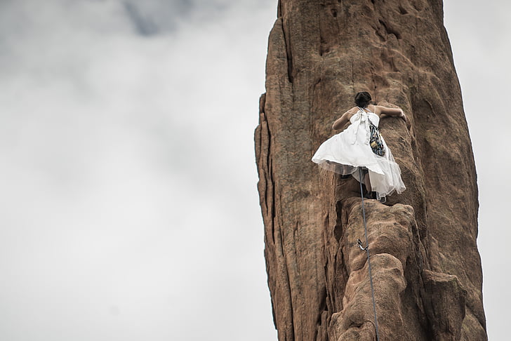 low angle photography of bride climbing rock formation
