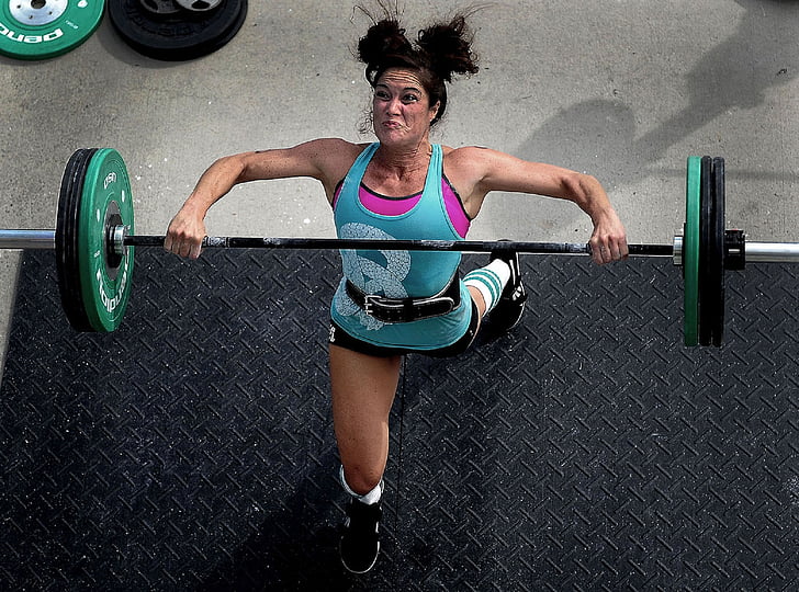 woman lifting barbell on black surface