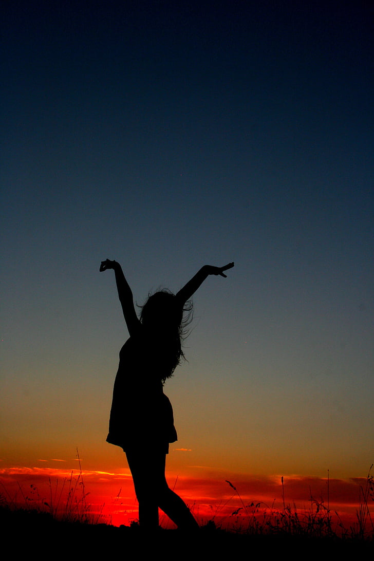 photography of woman raising her hands during sunset