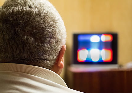 man in white shirt watching TV inside room