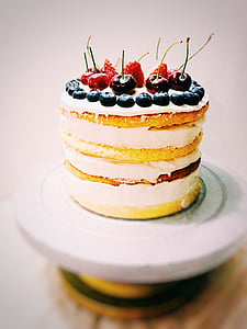 round white coated icing cake with cherry, strawberries and cranberries on top