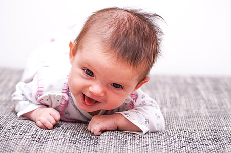 baby laughing while crawling on gray mat