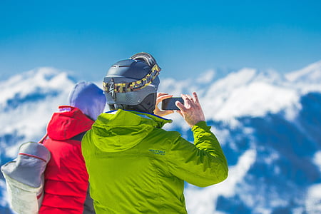 man at the peak of snowy mountain taking pictures