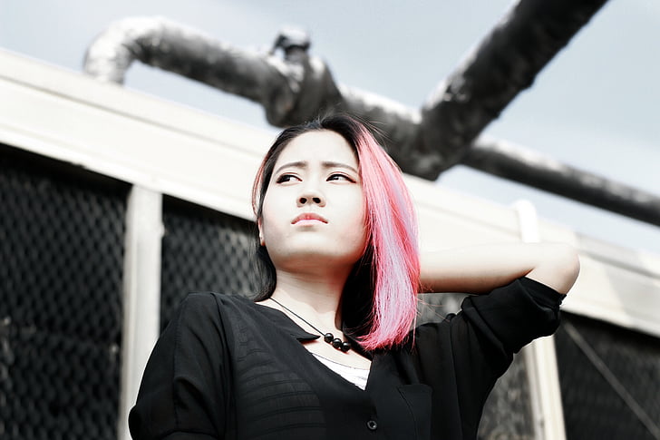 pink-haired woman wearing black shirt standing near white building