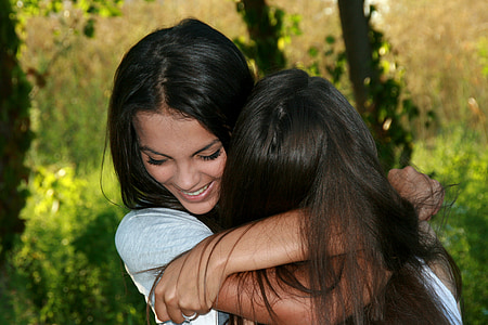closeup photo of two women hugging each other