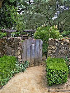 brown wooden gate mounted on concrete wall towards garden