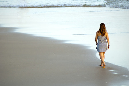 woman in gray sleeveless dress walking on white surface