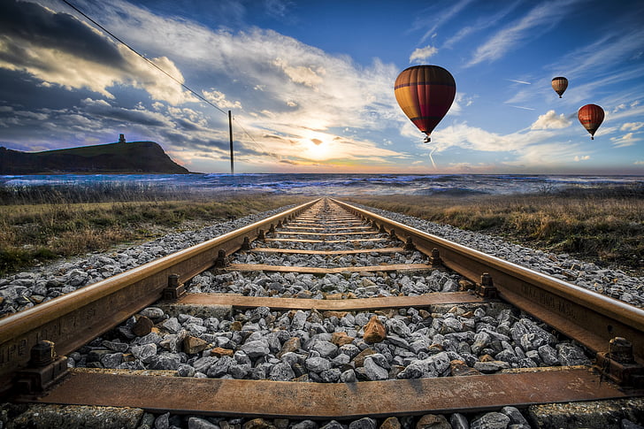 rusted trail rail near three hot air balloons during daytime