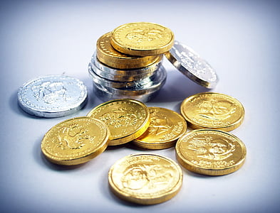 close-up photo of silver-colored and gold-colored coin lot on white surface