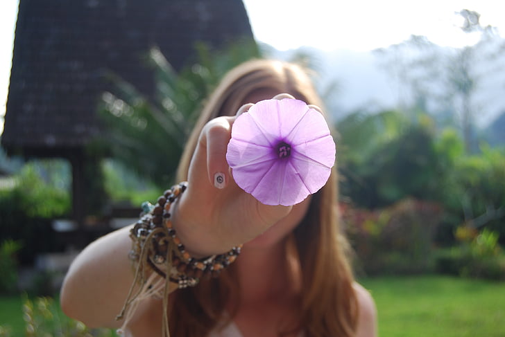 woman holding purple petaled flower