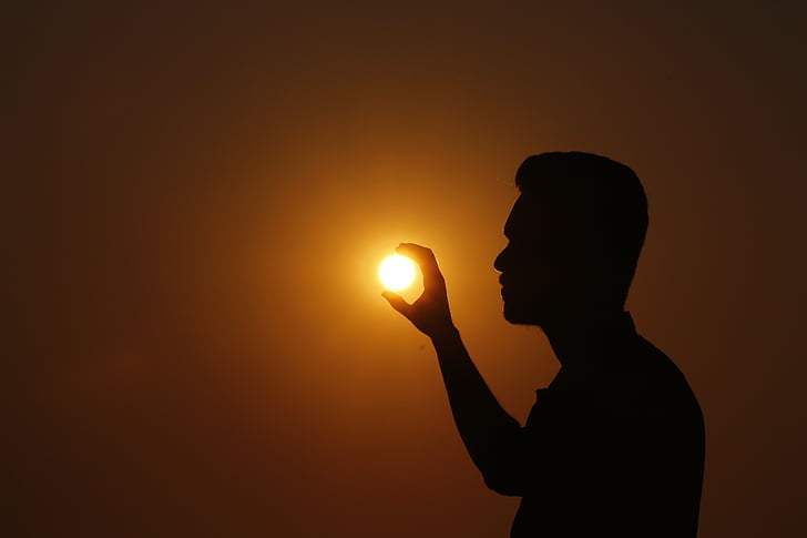 forced perspective photo of silhouette of man holding sun