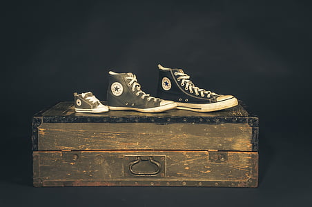 three unpaired Converse All-Star shoes on wooden trunk