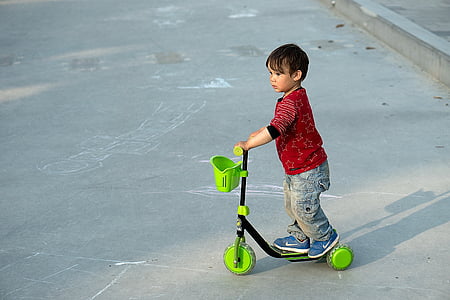 boy riding black and green 3-wheeled kick scooter