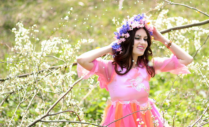 woman wearing pink dress and flower headdress beside tree branch