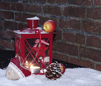 red apple fruit on lantern candle holder on snow