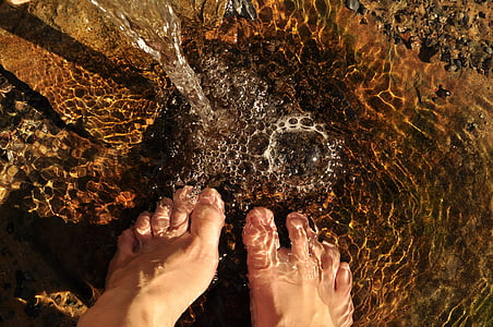 closeup photo of human feet on body of water