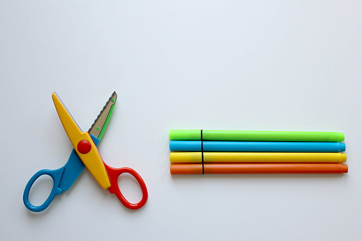 closeup photo of multicolored scissors and pens on white surface