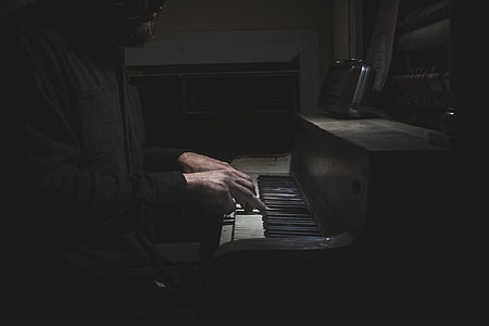 man sitting beside piano