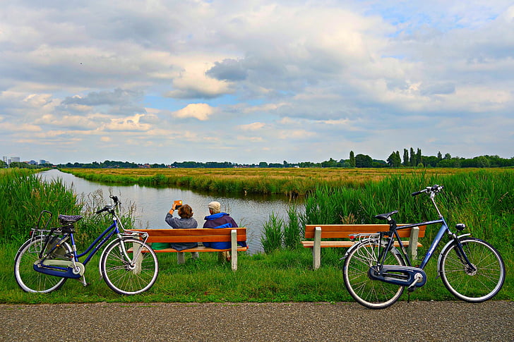 two bicycles on road with two people sitting on bench