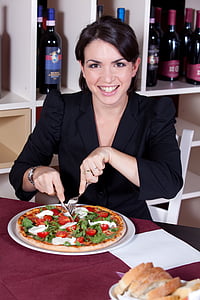 woman in black blazer seating on white chair beside pizza