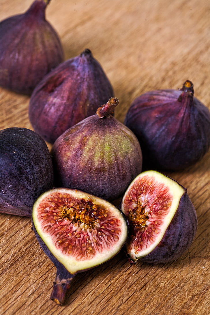 shallow focus photo of purple figs on brown wooden surface