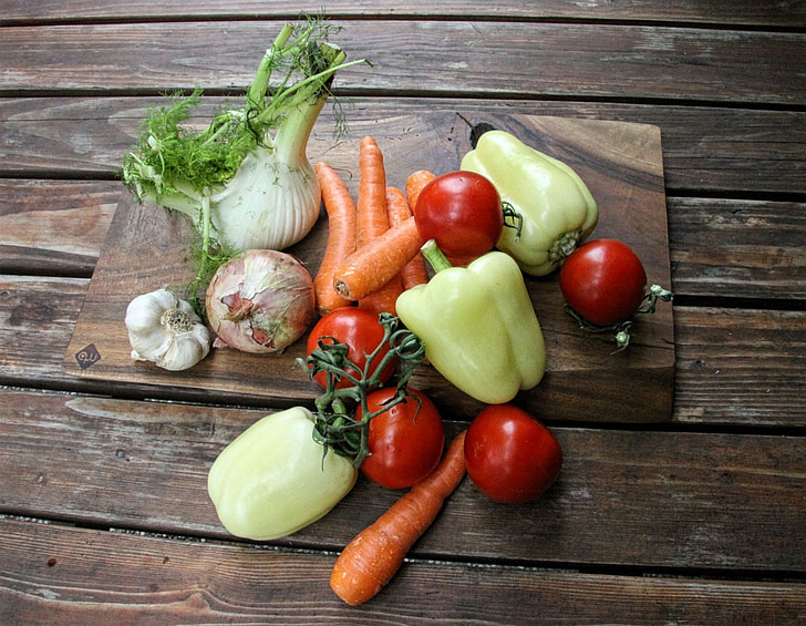 raw onion, carrots, bell pepper, and tomatoes on wooden cutting board