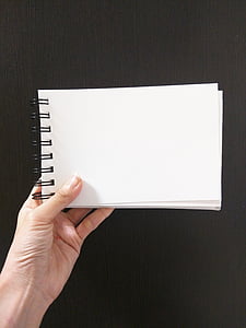 person holding white spiral notebook