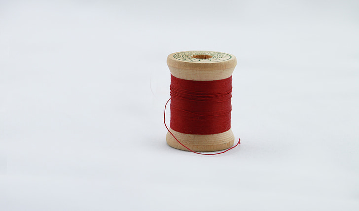 red thread spool on white surface