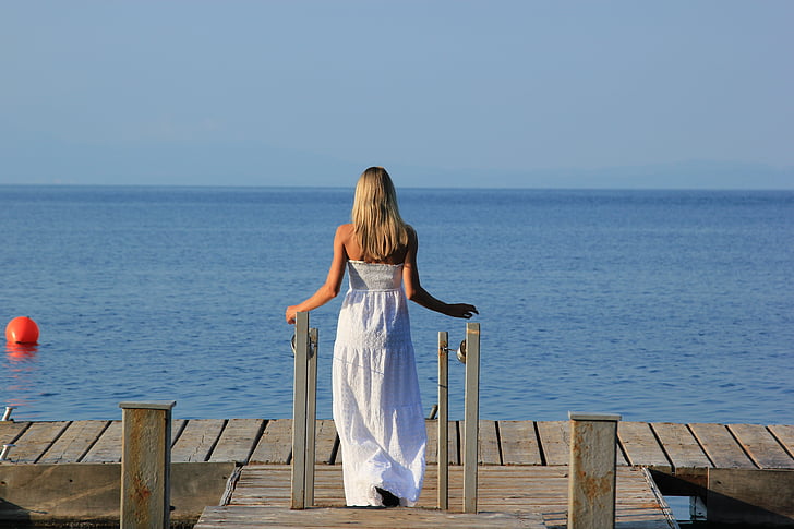 woman wearing white tube dress on brown wooden dock during daytime