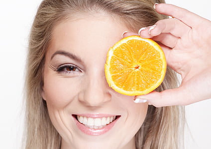 woman with brown hair holding sliced orange