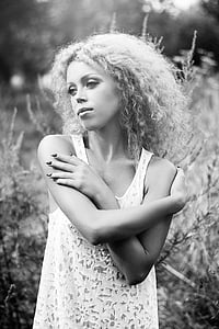 grayscale photography of woman wearing sleeveless top standing near plant