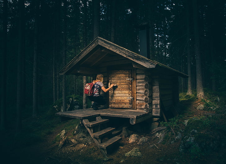 woman on wooden cabin in middle of forest