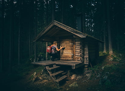 woman on wooden cabin in middle of forest