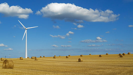 white windmill on brown hay field with rolls at daytime