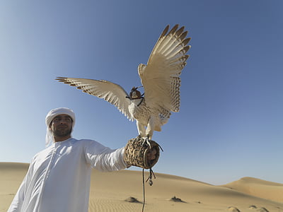man wearing white thobe coat holding white bird