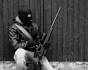 person in jacket holding sniper rifle