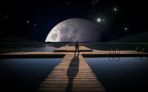 man standing on dock facing moon digital wallpaper