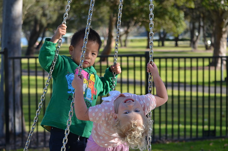 two toddler's riding on swing