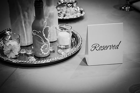grayscale photo of reserved sign on table