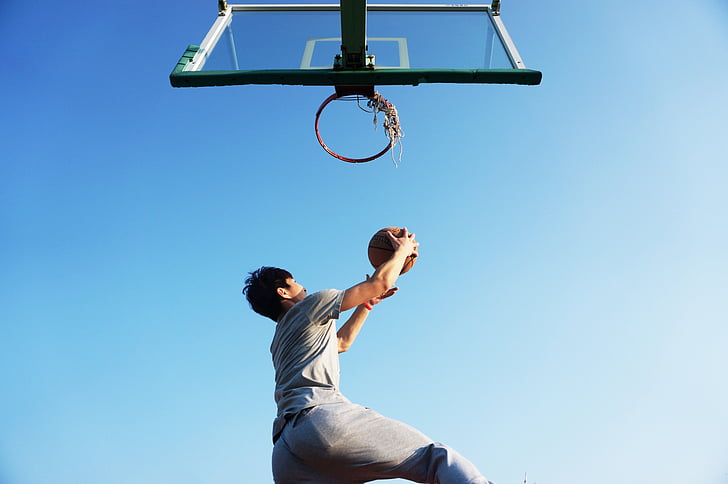 man holding ball near basketball hoop