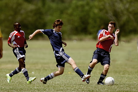 three male playing soccer