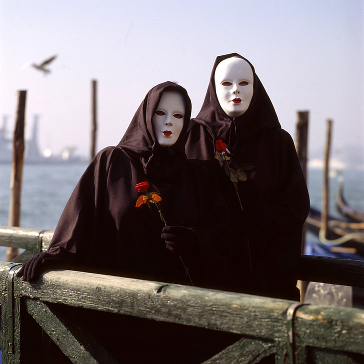 two person wearing black capes and white masks