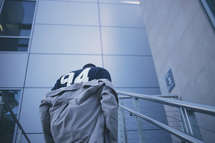 man taking off gray jacket standing on stair inside the building