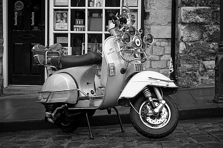 grayscale photo of motor scooter parked near house